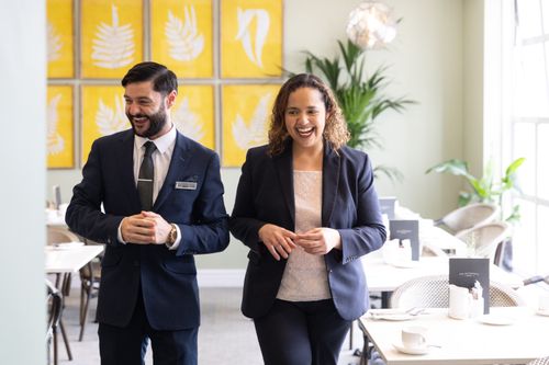 This image shows to people in corporate clothing smiling and laughing while walking